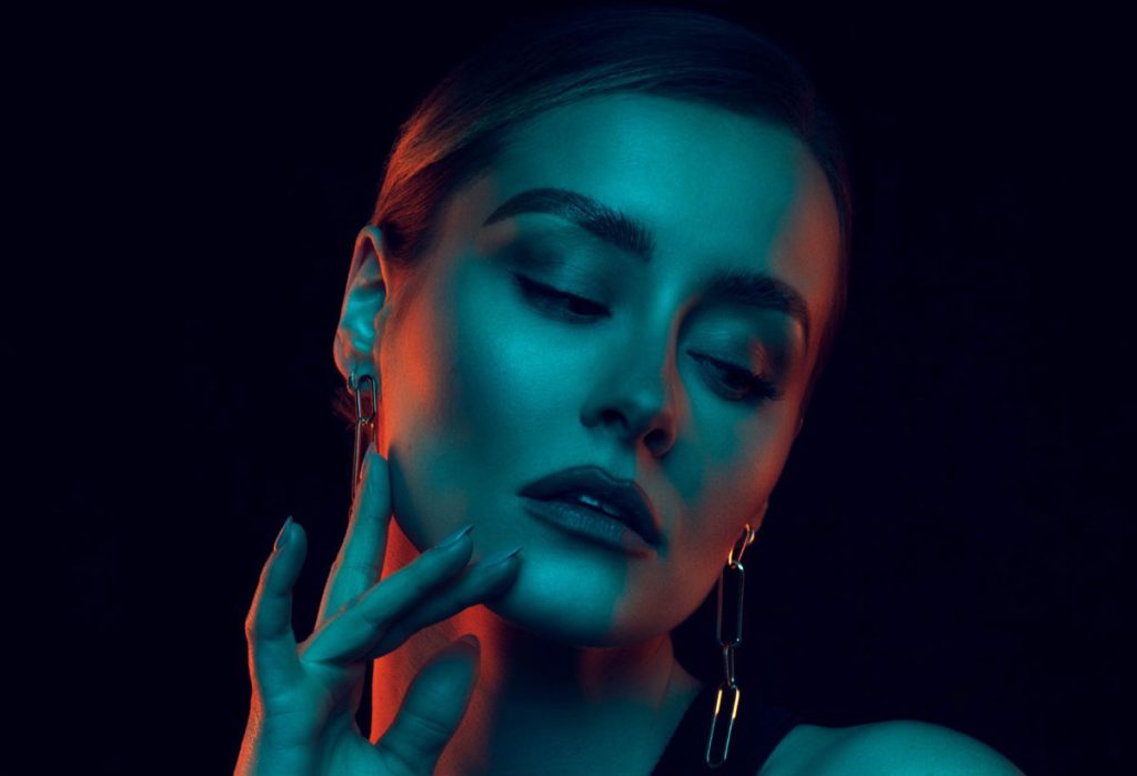 brown haiured model in orange and blue dark lighting